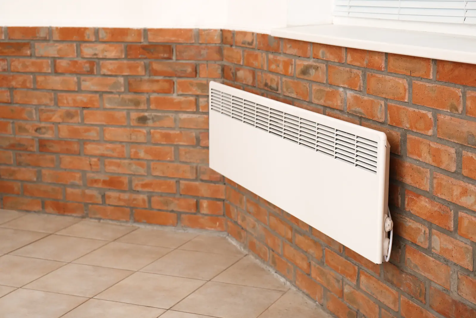Radiateur électrique fixé sur un mur de briques